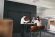 © Flamingo Images - Four mixed race business people sitting at a high table in an office community. They smile at each other and hold a meeting