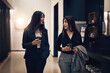 © Flamingo Images - Smiling businesswomen talking over coffee to go while walking through a hotel lobby