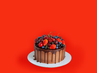 Wall Mural - Chocolate cake with fresh berries, strawberry, cherry, blueberry isolated on red background. Horizontal orientation