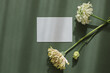 © RooM The Agency - Overhead view of a blank card on a table with lisianthus, gerbera and ranunculus flowers in sunlight