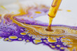 Detailed view of a cartilage sample undergoing staining in a laboratory, the dye creating vibrant patterns of yellow against a contrasting purple sample, isolated on a white background