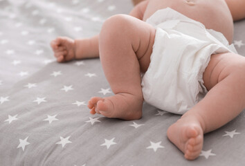 Sticker - Cute little baby in diaper lying on bed, closeup