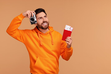 Canvas Print - Smiling man with passport, camera and tickets on beige background. Space for text