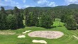 AERIAL: Panoramic drone view of lush golfing greens hidden deep in the pine forests. Neatly maintained course greens and bunkers nestled among lush trees are captured from an aerial perspective.