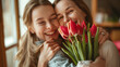 Two women joyfully embrace each other while holding a beautiful bouquet of tulips, Mother and daughter, Mother`s Day concept
