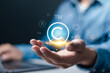 © Pakin - Copyright protection concept. Registration or registration for trademark, Register trademark. Businessman holding copyright icon and logo on virtual screen.