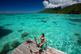 Fototapeta Londyn - Luxury beach travel vacation woman in Tahiti overwater bungalow hotel villa swimming. This image is completely unretouched and unedited and model is with no makeup. Original Raw Image.
