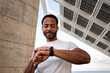 © Daniel - African American man checking pulse in smart watch. Black male with earphones using smart watch to put on music.