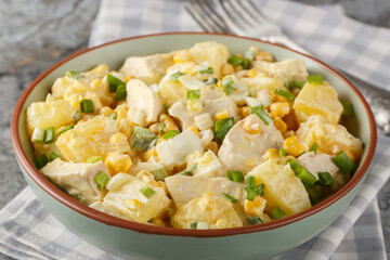 Wall Mural - Festive Chicken salad with fresh pineapple, corn, cheese, eggs and onions dressed with mayonnaise close-up in a plate on the table. Horizontal