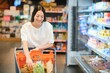 © Serhii - Young smiling happy woman 20s in casual clothes shopping at supermaket store with grocery cart