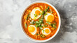Flavorful Fried Egg Curry served in a white bowl on a light grey background.