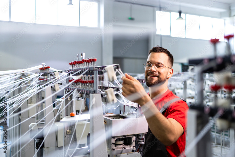 Worker preparing industrial knitting machine for work in textile ...