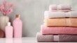 Colored terry towels in a stack on a light background, folded soft bath towels, cosmetics in the background. Bathroom.