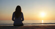 © Issah - Silhouette of a woman sitting on the sandy beach at sunset