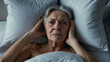 grey-haired, old woman lies in bed with open eyes, concept of senile insanity.
