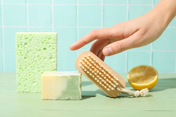 Wall Mural - Sponge, bar of soap, lemon, brush and hand on blue background