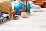 Fototapeta Tęcza - Travel planning simple background of compass, film camera, straw hat, globe and New York and Paris souvenirs on white planks low angle with copy-space