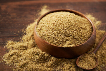 Wall Mural - close up ground powder coriander seed in wood bowl on rustic table food background