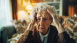 © lelechka - An elderly woman sits looking confused with her head in her hands.
