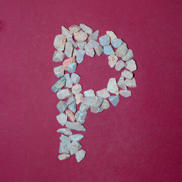Letter P made of white stones. Creative alphabet concept on a red background. 
