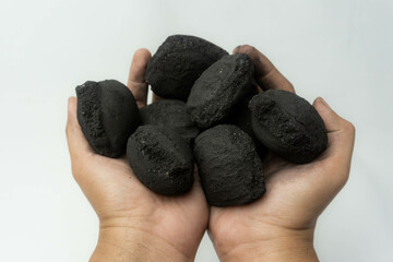 hand holding charcoal briquettes isolated on a white background, suitable for BBQ cooking