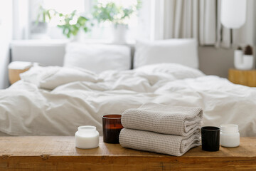 Wall Mural - Selective focus on wooden shelf with towels and candles against blurred bedroom interior