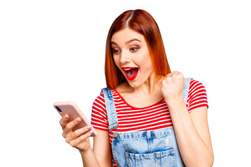 Wall Mural - Nice vivid girlish red straight-haired happy smiling girl reading sms notification about winning, isolated over blue background, copy space