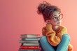 Young girl in glasses sitting on stack of books against pink background in education concept