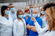 Healthcare team with surgical masks looking at ampule with dangerous virus. Doctors, nurses, professionals in medical uniforms and face masks in hospital.