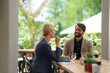 © Halfpoint - Couple sitting outdoors on terrace restaurant, having dinner date. Business lunch for two managers, discussing new business project.