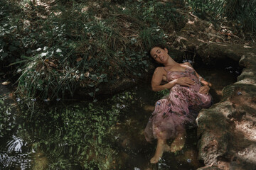 Person meditating and dreaming while she floats in the water of a natural environment. Concept of spiritual connection with the natural environment and ethereal atmosphere between two worlds.