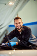 © bnenin - A mechanic man is working in his garage while smiling for the camera.