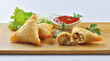 Chicken Samosa with ketchup and one samosa is broken to show samosa filling