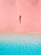 Woman lying on pink beach with blue sea in Komodo national park