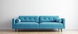 A violet studio couch is placed in front of a white wall in a living room, providing comfort and style. The rectangular furniture piece complements the flooring