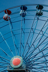 Wall Mural - Colorful ride ferris wheel in motion in amusement park on sky background.