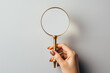 A female hand holding a magnifying glass on a light background. Mockup with empty copy space for a text and design