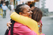 Senior multiracial women meeting and hugging each other outdoor - Friendship, no racism and lifestyle concept - Focus on african female face