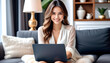 © anmitsu - A beautiful young female freelancer is sitting on a comfortable sofa and browsing the internet on her laptop to run a successful business. Luxurious interior. Work from home concept.