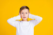 Photo of shocked amazed kid dressed white shirt arms close ears empty space isolated yellow color background