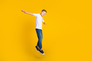 Wall Mural - Full length photo of positive funky kid dressed white shirt jumping high flying empty space isolated yellow color background