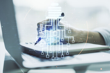 Poster - Creative light bulb with chip hologram and hand writing in notepad on background with laptop, artificial Intelligence and neural networks concept. Multiexposure