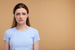 Portrait of sad woman on beige background, space for text