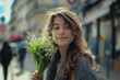 French woman with small bunch of lily of the valley on a street of Paris. French tradition to offer lily of the valley on the 1st of May, International Workers Day which is a public holiday in France