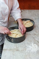 Wall Mural - A confectioner girl decorates and decorates traditional Easter cake with pigtail woven from the dough. Easter cake is an easter spring holiday symbol