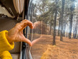 © simona - Woman puts her hand on the glass forming a heart with the reflection. Concept of play and love for nature