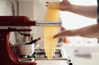 Fresh homemade pasta noodles being prepared with a kitchen appliance.