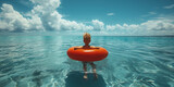 Fototapeta Londyn - baby swims in the sea on an orange inflatable ring