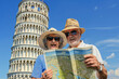 Portrait of smiling senior couple with map and city guide above leaning tower of Pisa 