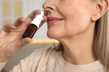 Poster - Medical drops. Woman using nasal spray indoors, closeup